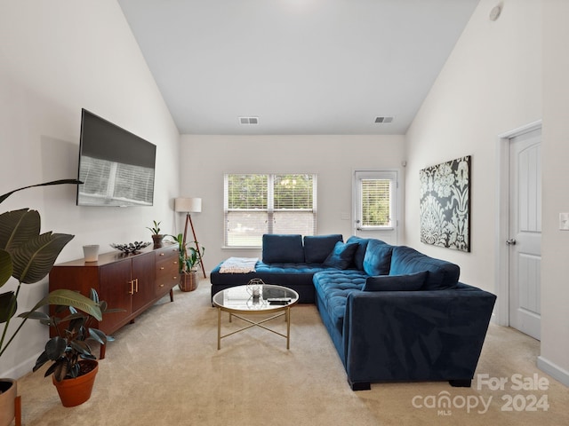 living room with light colored carpet and high vaulted ceiling