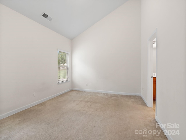 carpeted spare room featuring high vaulted ceiling