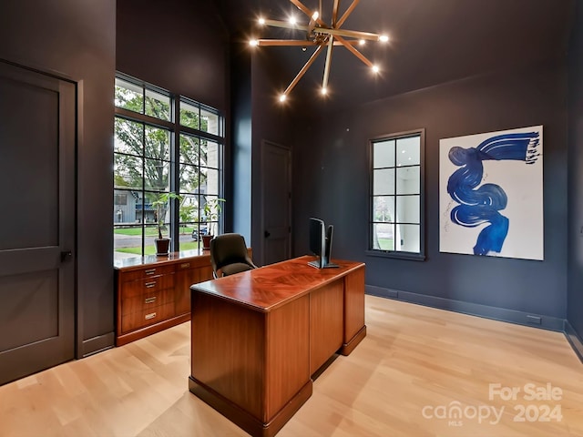 home office with a notable chandelier and light hardwood / wood-style flooring