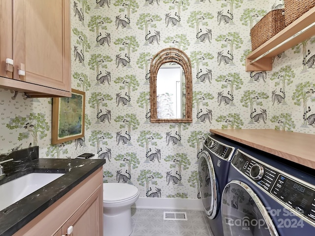 bathroom featuring tile patterned flooring, washing machine and dryer, toilet, and vanity