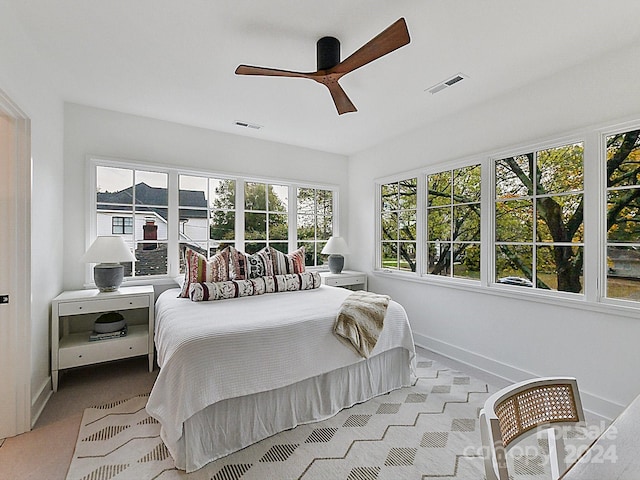 bedroom featuring ceiling fan, multiple windows, and light carpet