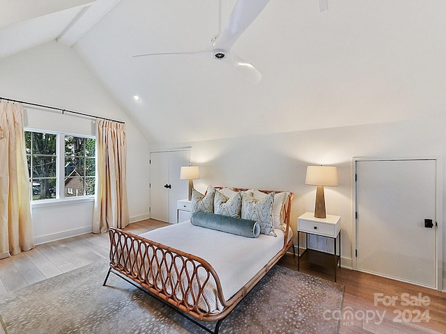 bedroom with lofted ceiling with beams and wood-type flooring