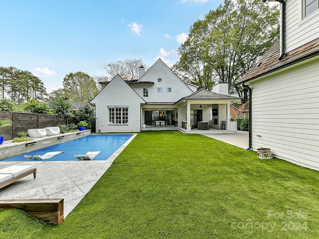 back of property with a yard, a fenced in pool, and a patio area