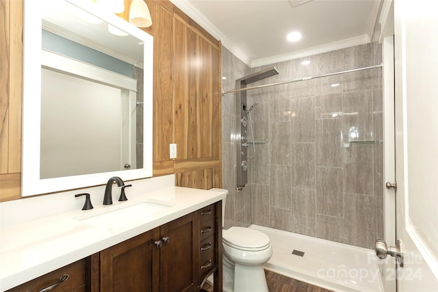 bathroom featuring toilet, tiled shower, vanity, and crown molding