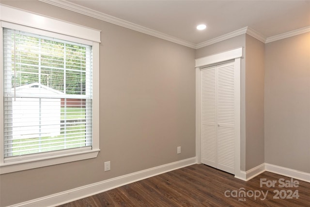 unfurnished bedroom with dark wood-type flooring, a closet, and ornamental molding