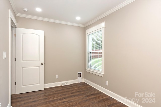 empty room featuring dark wood-type flooring and crown molding