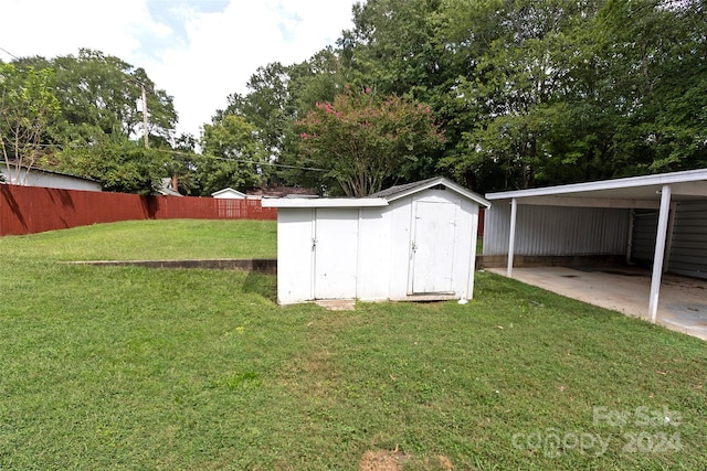 view of outdoor structure with a carport and a lawn