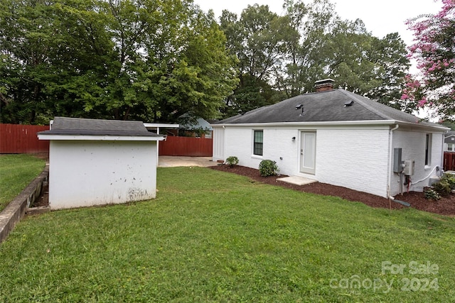 back of property with a storage unit and a yard