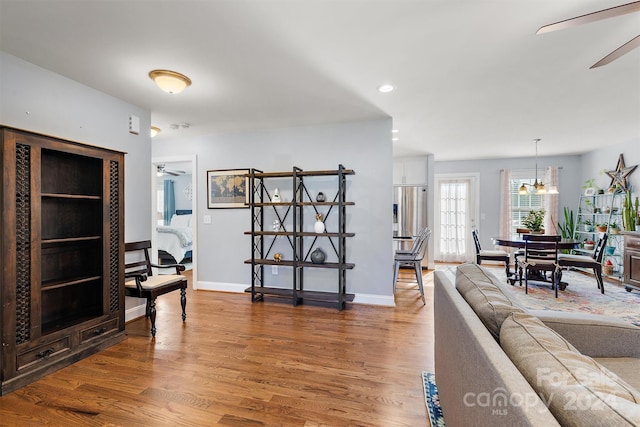 living room with ceiling fan with notable chandelier and hardwood / wood-style flooring