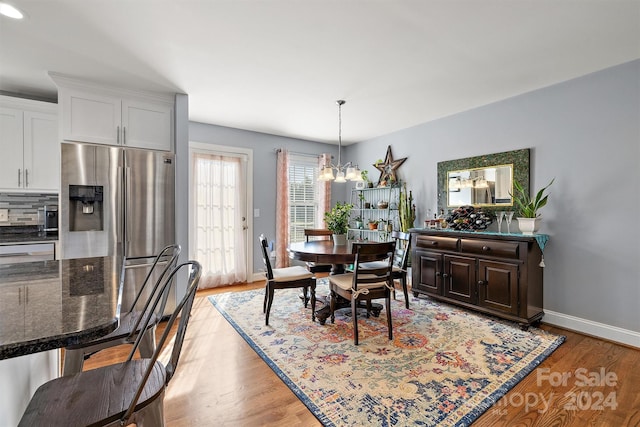 dining room with light hardwood / wood-style floors and a notable chandelier