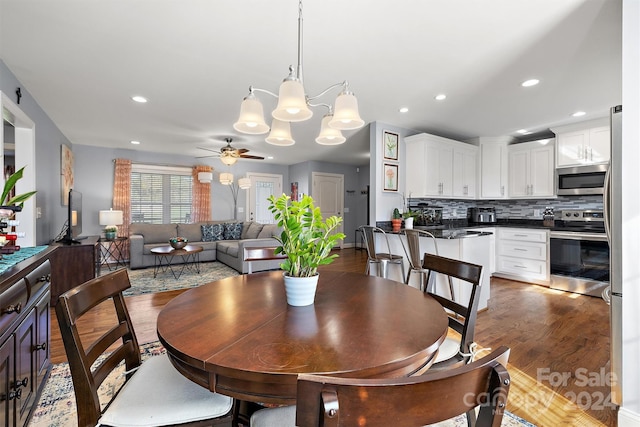 dining room featuring ceiling fan with notable chandelier and dark hardwood / wood-style flooring