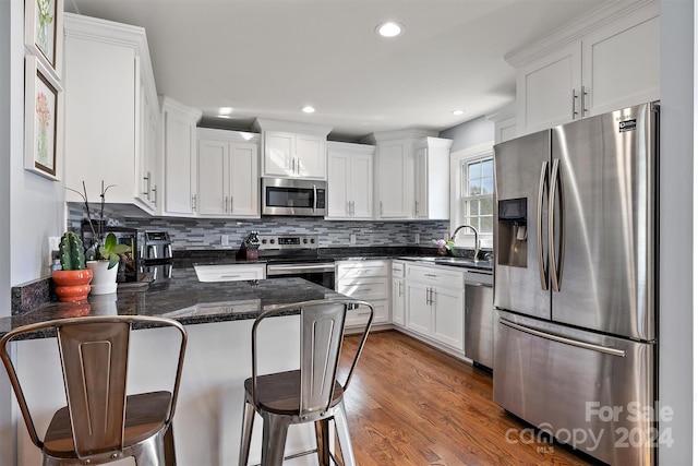 kitchen featuring kitchen peninsula, appliances with stainless steel finishes, dark hardwood / wood-style floors, and white cabinetry