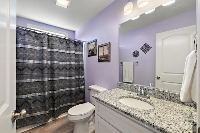 bathroom featuring wood-type flooring, vanity, toilet, and walk in shower