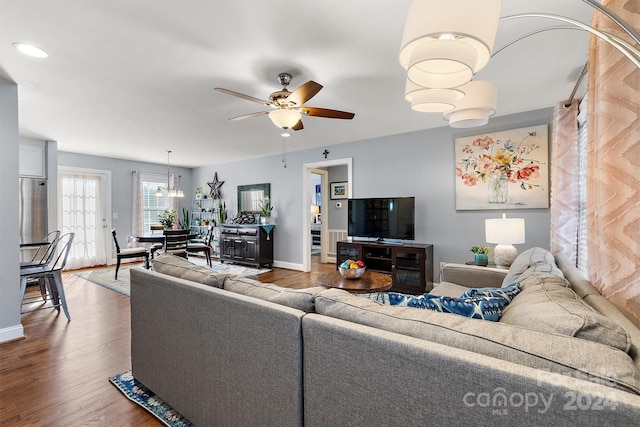 living room with ceiling fan with notable chandelier and hardwood / wood-style flooring