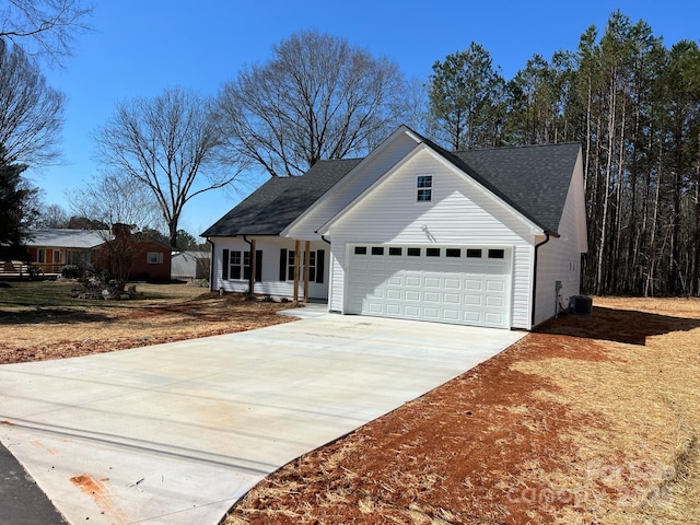 view of front facade featuring concrete driveway, an attached garage, central AC unit, and roof with shingles