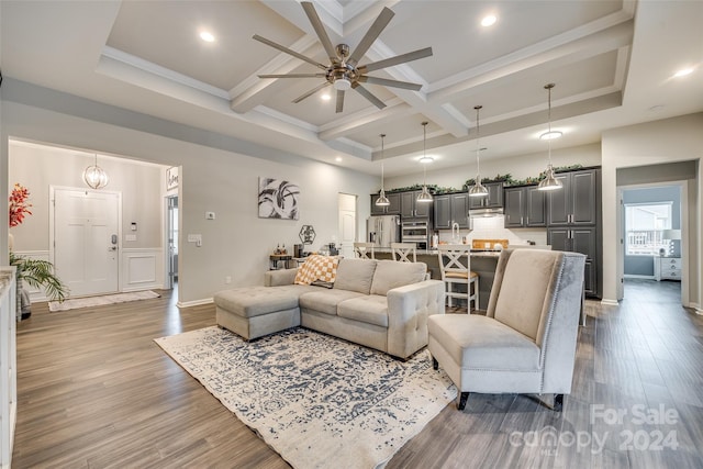 living room featuring wood-type flooring, ornamental molding, coffered ceiling, beamed ceiling, and ceiling fan