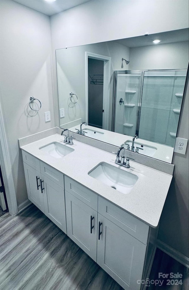 bathroom with hardwood / wood-style floors, vanity, and a shower with door