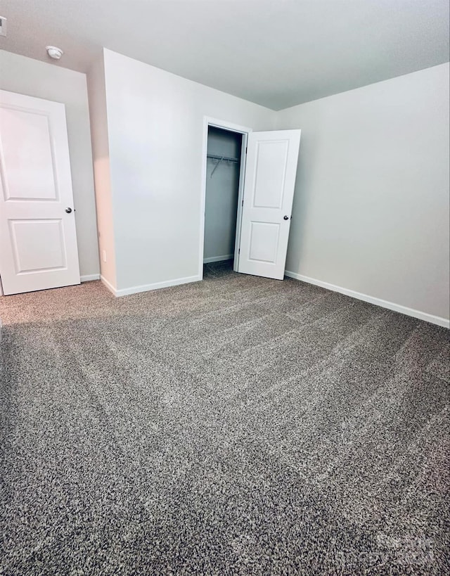 unfurnished bedroom with a spacious closet, carpet floors, and a closet