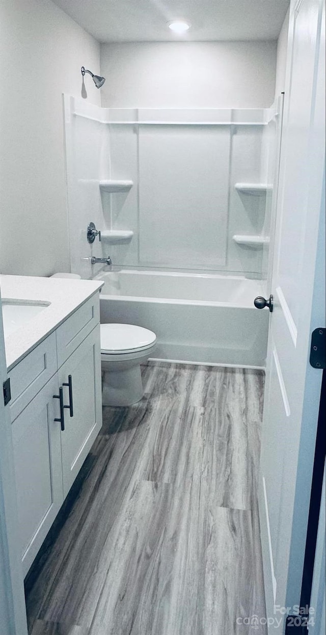 full bathroom featuring hardwood / wood-style floors, vanity, toilet, and bathtub / shower combination