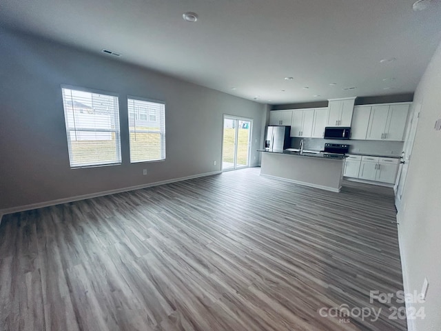 kitchen with a kitchen island with sink, hardwood / wood-style flooring, black electric range, stainless steel fridge with ice dispenser, and white cabinetry