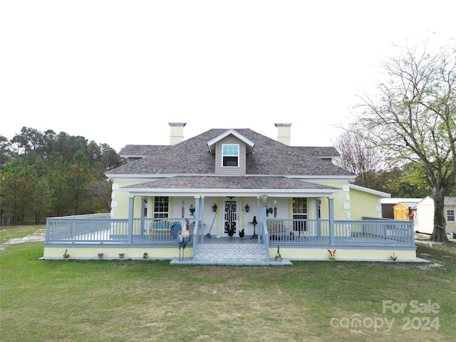 view of front facade with a front yard, a storage shed, and covered porch