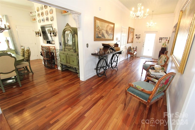 living area with hardwood / wood-style floors, an inviting chandelier, and ornamental molding