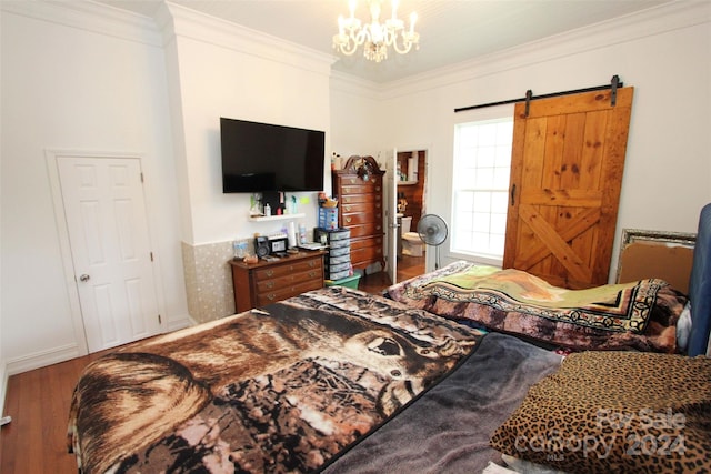 bedroom featuring wood-type flooring, a barn door, an inviting chandelier, and ornamental molding