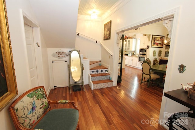 stairs with wood-type flooring and ornamental molding