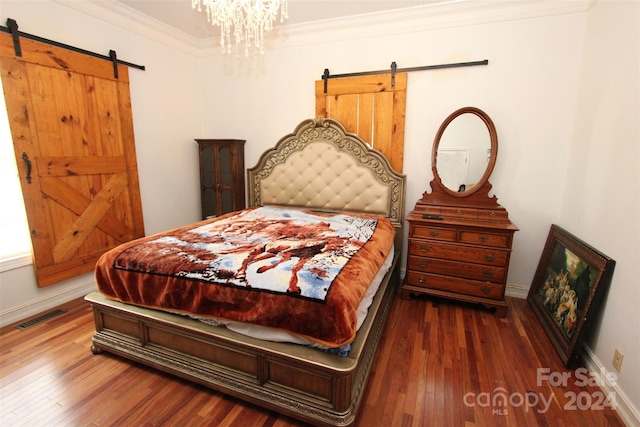 bedroom with a chandelier, ornamental molding, a barn door, and dark wood-type flooring