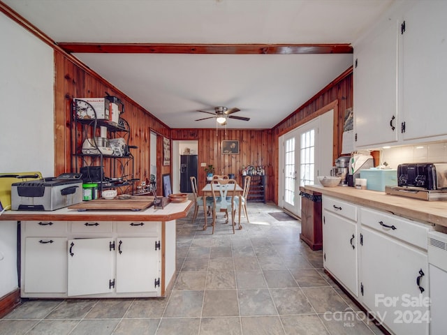 kitchen featuring white cabinetry, french doors, ceiling fan, wooden walls, and black fridge with ice dispenser