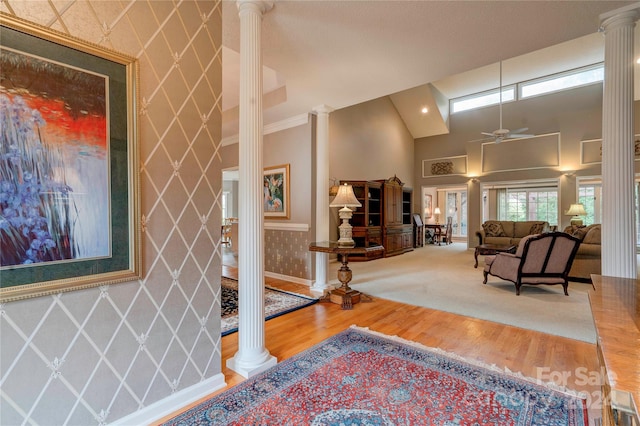 foyer with ceiling fan, hardwood / wood-style floors, ornate columns, and a towering ceiling