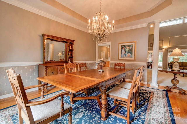 dining area with crown molding, hardwood / wood-style flooring, ornate columns, and a raised ceiling