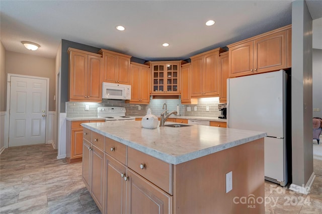 kitchen featuring a kitchen island with sink, sink, white appliances, and backsplash