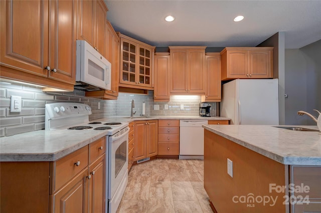 kitchen with decorative backsplash, white appliances, sink, and a kitchen island