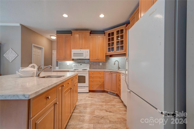 kitchen featuring tasteful backsplash, sink, white appliances, and an island with sink