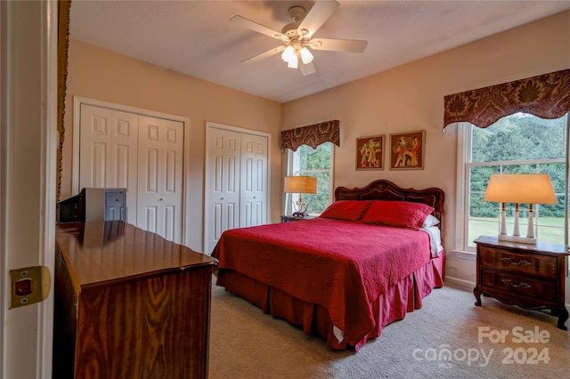 carpeted bedroom with ceiling fan and multiple closets