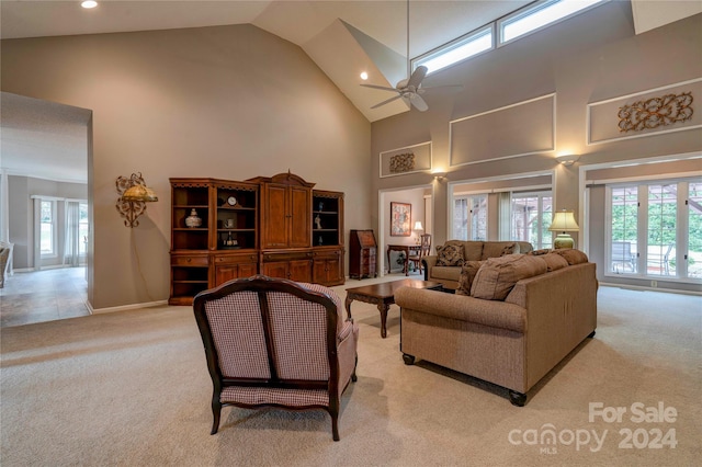 living room with ceiling fan, a healthy amount of sunlight, light carpet, and high vaulted ceiling