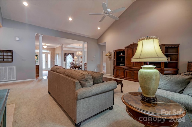 carpeted living room featuring ceiling fan with notable chandelier, high vaulted ceiling, and decorative columns