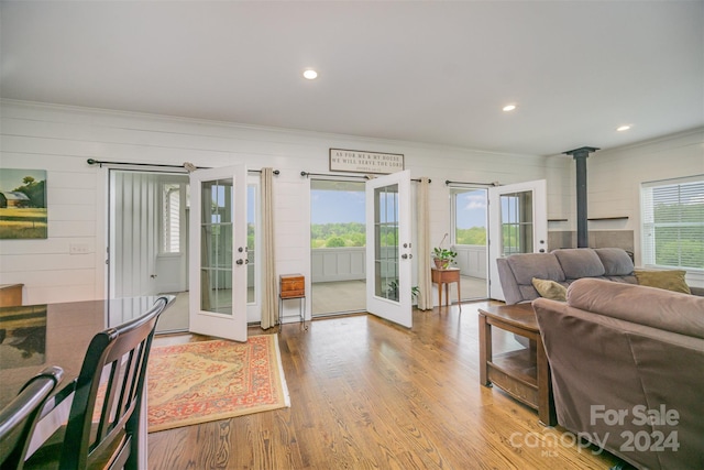 living room featuring french doors, light hardwood / wood-style flooring, plenty of natural light, and ornamental molding