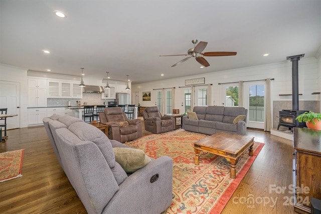 living room featuring a wood stove, dark wood-type flooring, french doors, ceiling fan, and ornamental molding