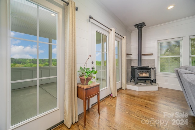 office with hardwood / wood-style floors, a wood stove, and crown molding