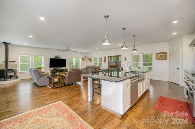 kitchen featuring a kitchen bar, light hardwood / wood-style flooring, dishwasher, white cabinets, and an island with sink