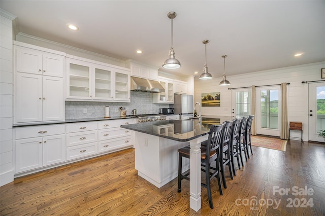 kitchen with dark wood-type flooring, a center island with sink, white cabinets, decorative light fixtures, and extractor fan