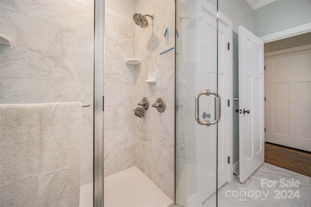 bathroom featuring hardwood / wood-style flooring, a shower with door, and crown molding