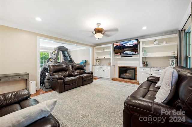 living room with ornamental molding, light hardwood / wood-style flooring, and ceiling fan