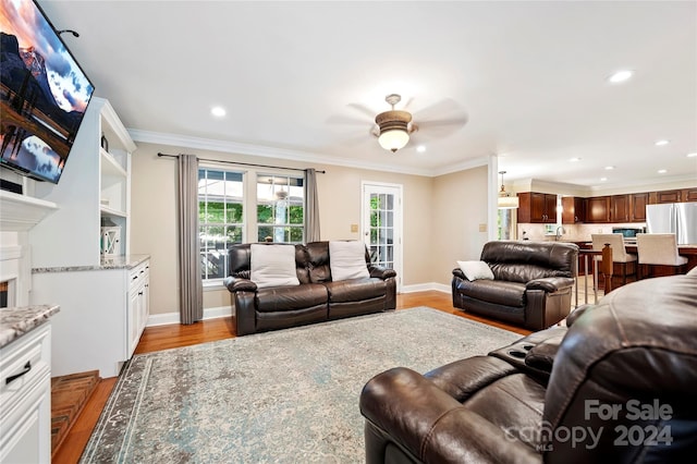 living room featuring crown molding, ceiling fan, and light hardwood / wood-style flooring