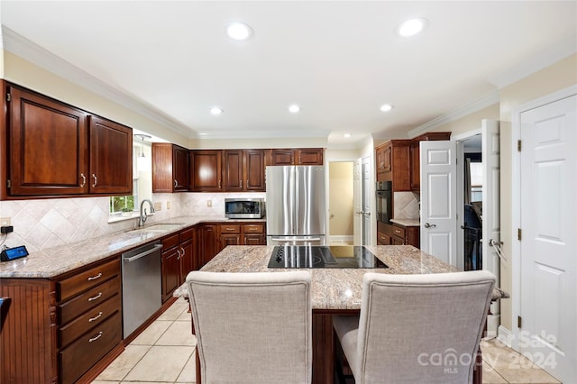 kitchen with sink, a breakfast bar, black appliances, tasteful backsplash, and a center island