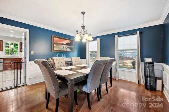 dining area with wood-type flooring, crown molding, and an inviting chandelier