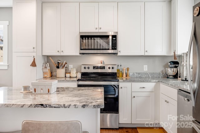 kitchen with stainless steel appliances, light stone countertops, and white cabinets