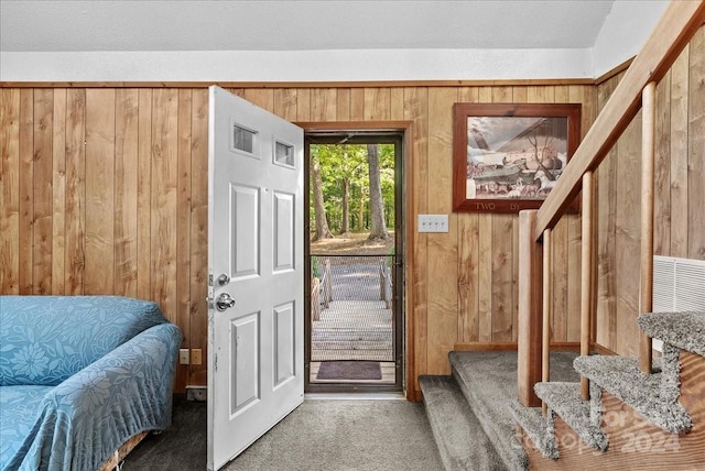 doorway to outside with carpet and wooden walls